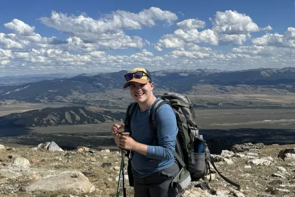 Nico Montag standing with a backpack with mountains in the background