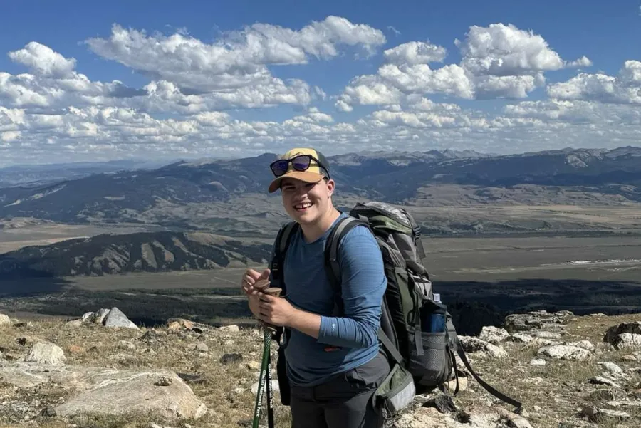 Nico Montag standing with a backpack with mountains in the background